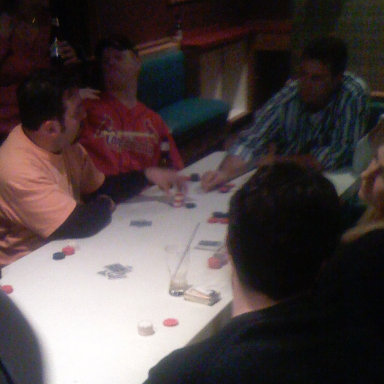 A group of people playing poker at a table with cards and chips.
